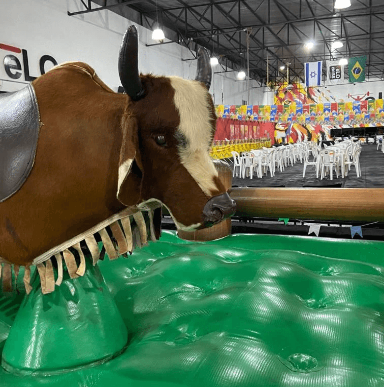 Touro mecânico da Virô montado sobre o colchão inflável verde, num salão de festa